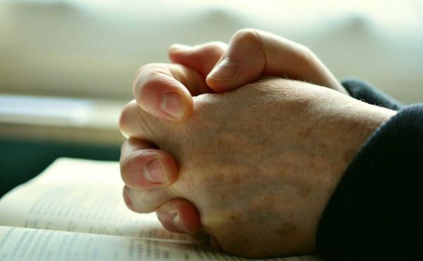 Hands folded on bible