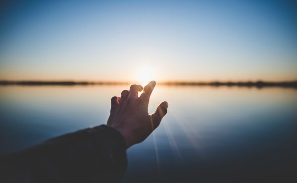 Hand reaching towards the sun