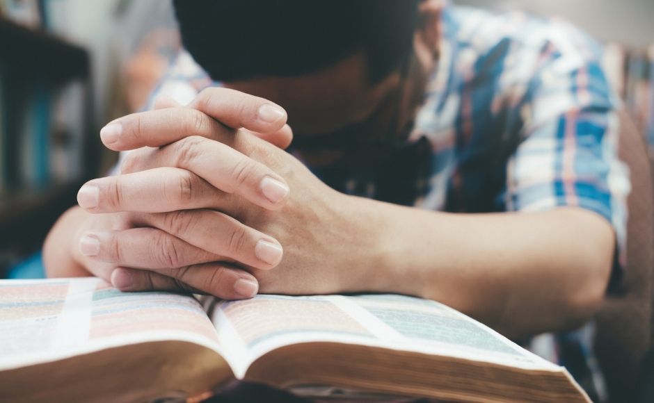 Man's hands on a Bible praying.