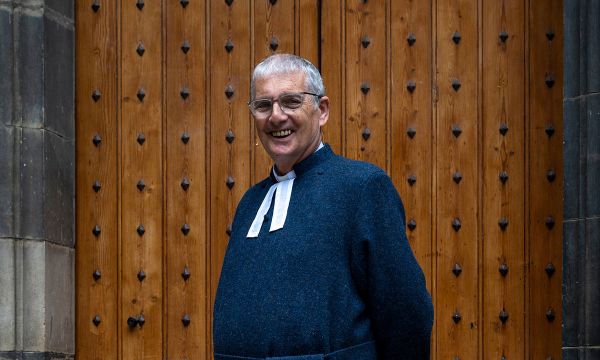 Iain Greenshields standing in front of wooden doors smiling