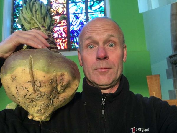Rev Stewart Weaver lifts up a  turnip as he celebrates harvest