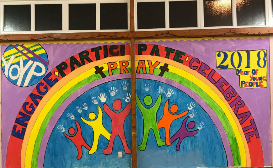 A mural depicting a rainbow, a cross and the year of young people logo