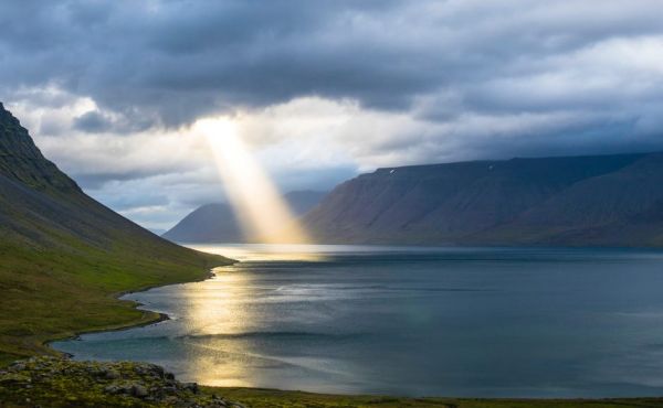 Beam of light shining on loch surrounded by mountains