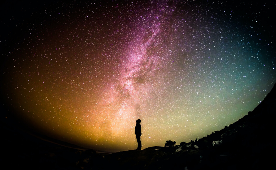 Man looking up at the galaxies in the night sky