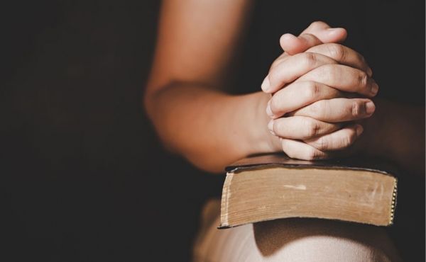 Praying hands on a Bible