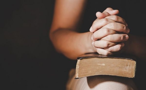 Praying hands over a Bible