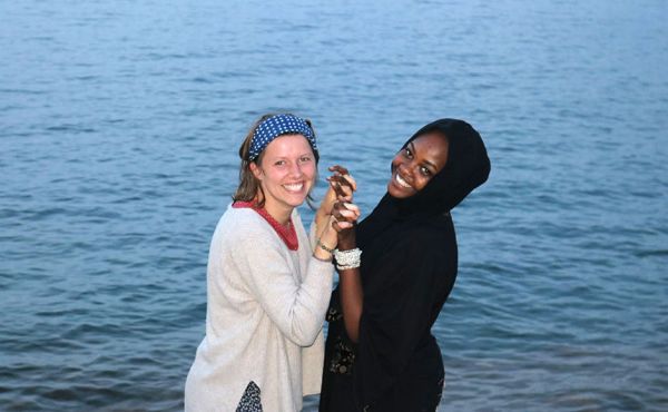 Two women holding hands in front of a body of water