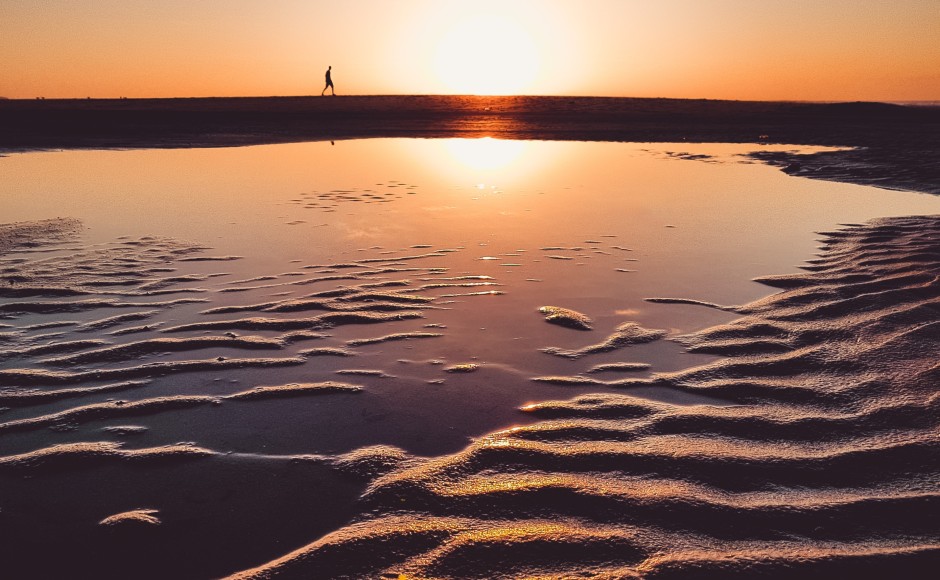 A figure walking along water