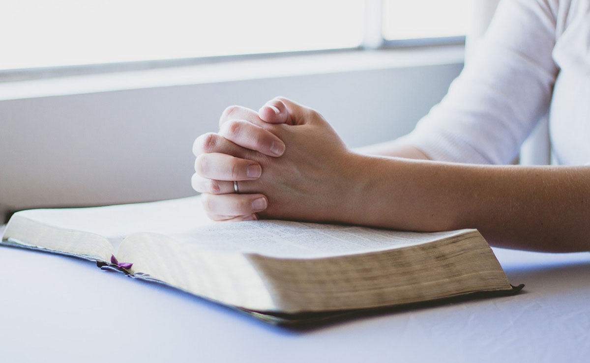 Hands folded over an open bible