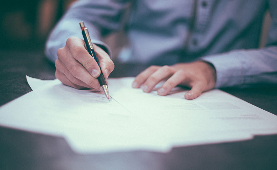 Close up of someone signing paperwork