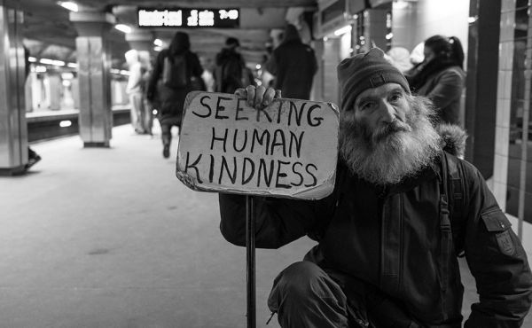 Elderly man with a sign that reads seeking human kindness