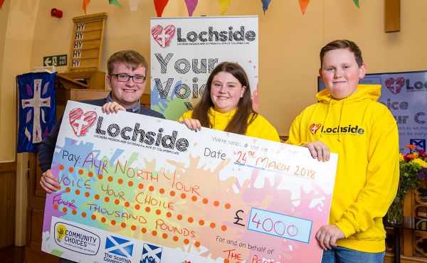 Dylan Harper, Project Leader at Lochside Mission and Outreach, presenting a cheque to Robbie and Megan, who won £750 for their holiday project