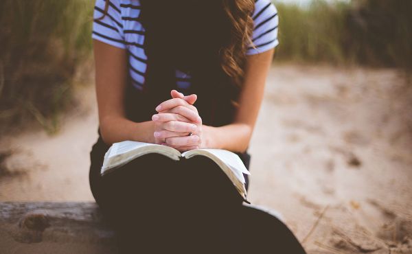 young woman praying on beach