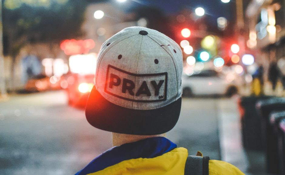 young man wearing cap with pray written on it