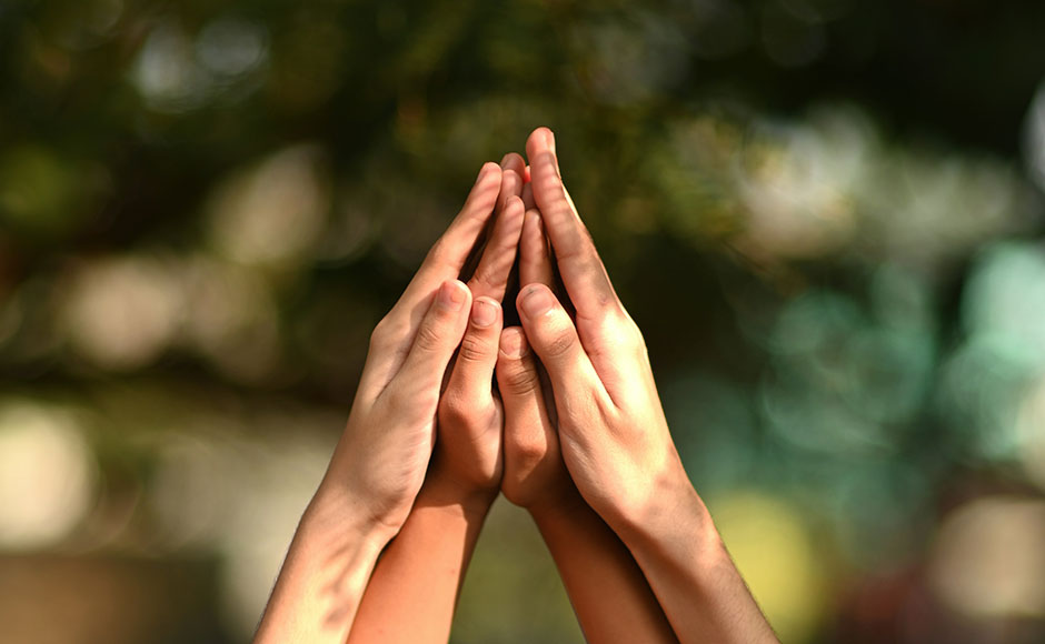 Two pairs of hands raised in prayer