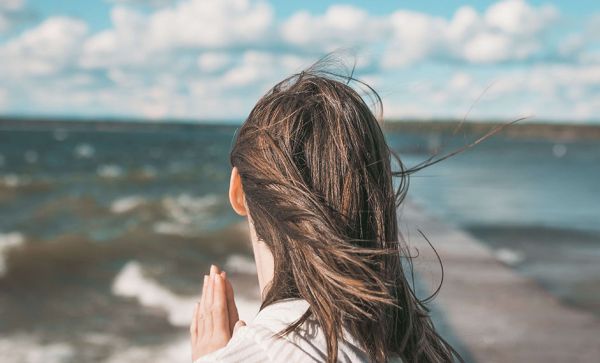 Woman with praying hands looking out to sea