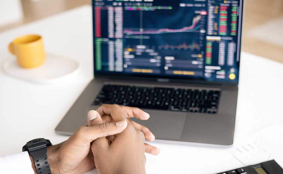 Person with hands folded looking at a computer screen with charts and graphs