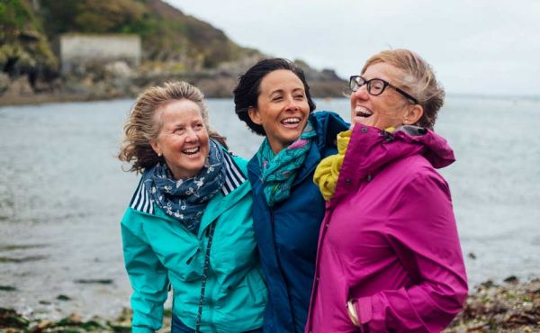 Group of ladies laughing walking along a beach