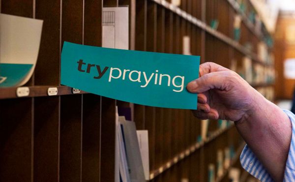 Hand holding a Try Praying sign