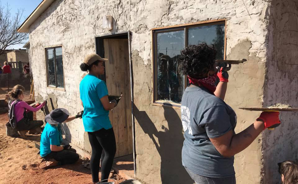 Applying the second coat of cement mixture to the walls of one of the new houses.