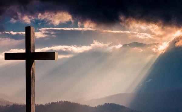 A cross sitting on a hill at sunset